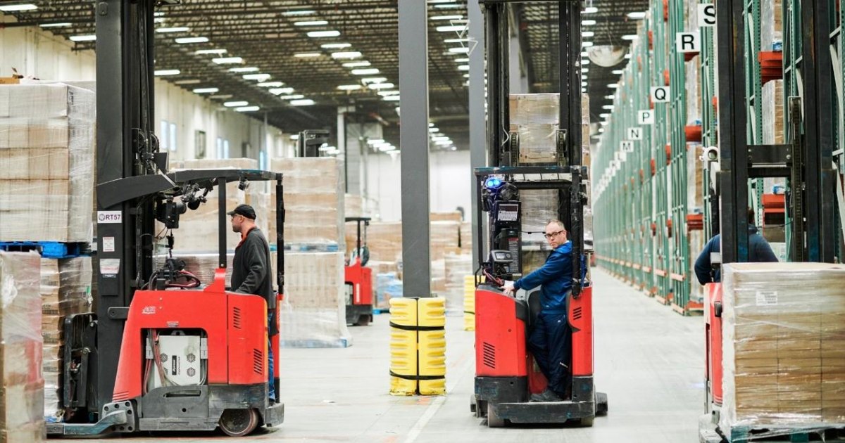 Two reach trucks with operators working in a busy warehouse aisle