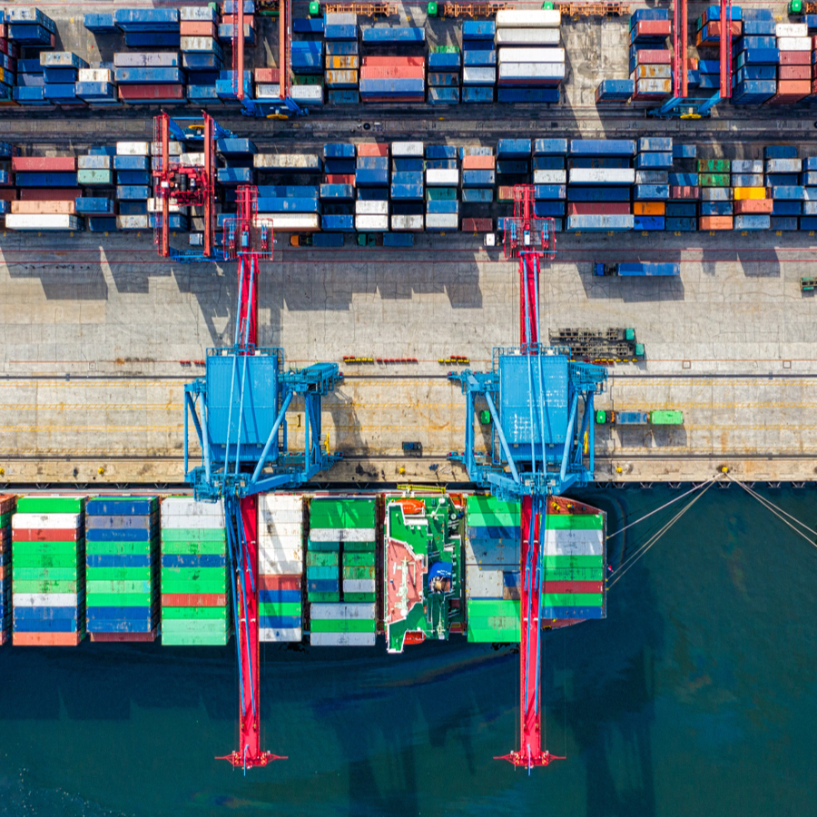 Aerial view of a container port with cranes loading stacked shipping containers