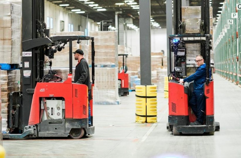 Forklifts working between warehouse racks with a person nearby